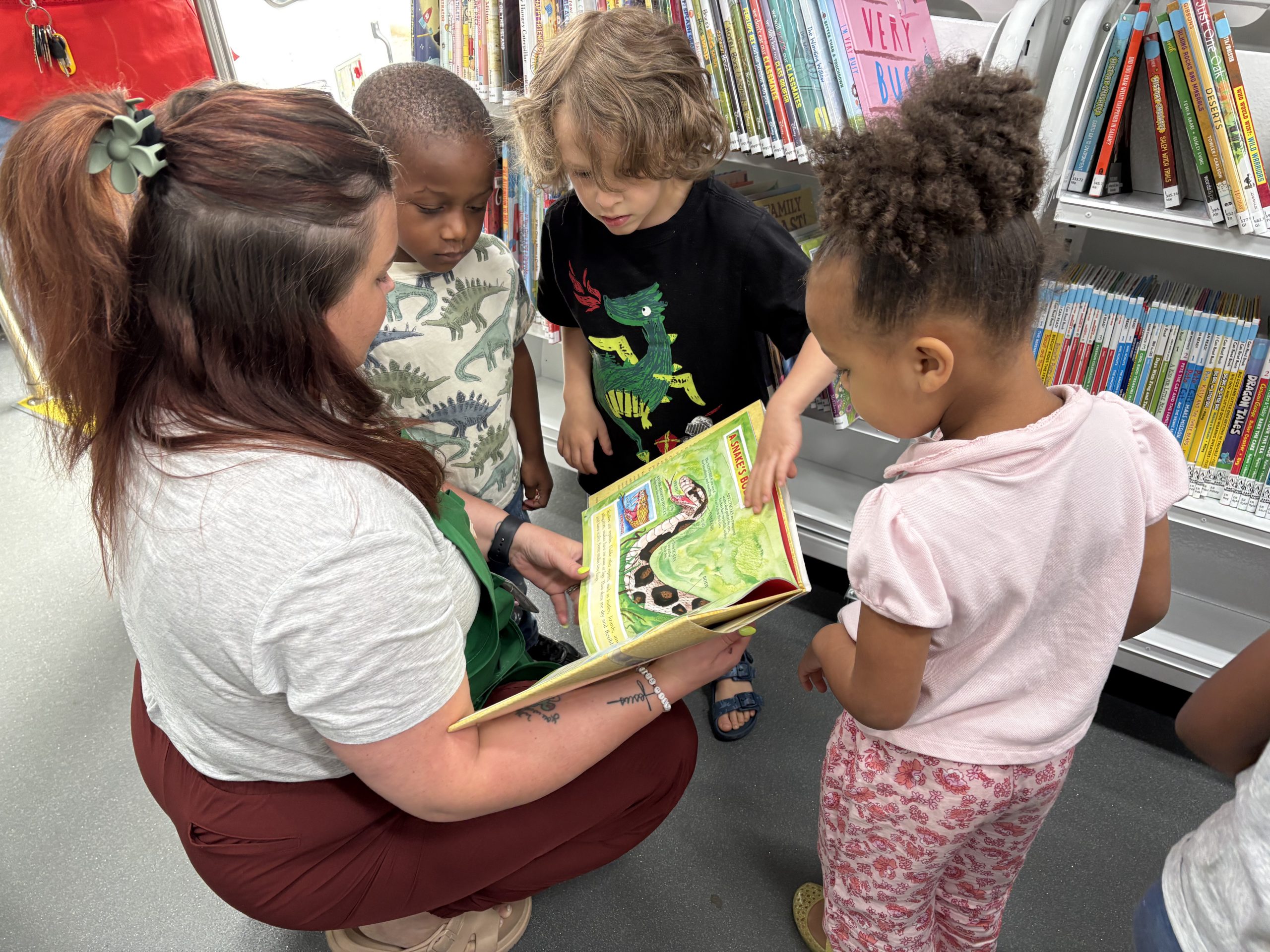 A teacher reads a picture book to a group of children on the bookmobile.